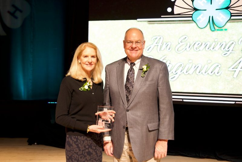 A woman holds a glass award, standing beside a man.