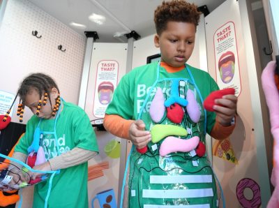 Two children wearing green shirts with plushie organs attached to it