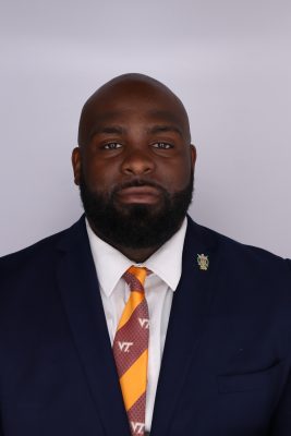 Black man with beard wearing a suit and striped tie