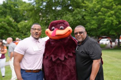 Two people pose with the Hokie Bird at an alumni tailgate